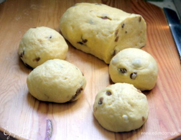 Поднявшееся тесто обмять и нарезать на кусочки примерно по 50 гр.
Придать кусочком круглую форму. Если вылезет изюминка, пальцем отправить её обратно вглубь теста, иначе она подгорит.