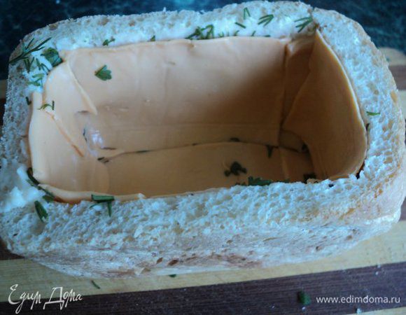 Смазать стенки и дно хлеба внутри тонким слоем мягкого плавленого сыра, посыпать зеленью и выложить пластинками сыра.
