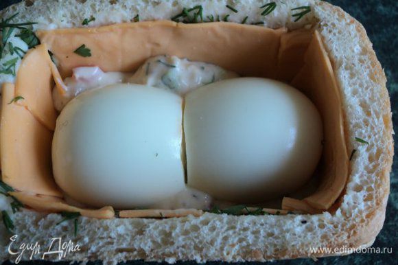 Выложить в хлеб на ½ высоты сырную смесь, положить в середину отваренные яйца.