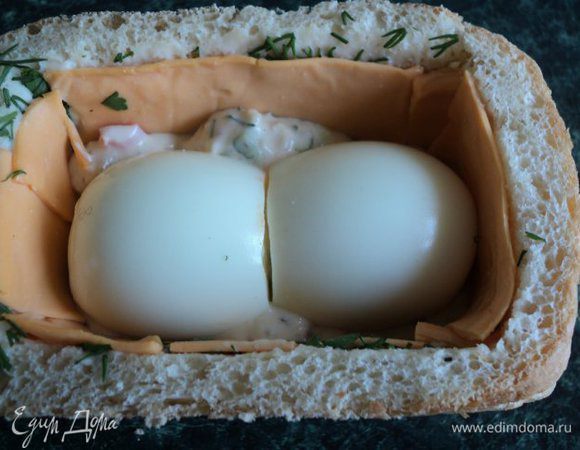 Выложить в хлеб на ½ высоты сырную смесь, положить в середину отваренные яйца.