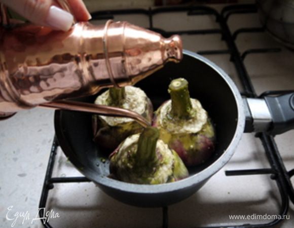 Поставить в сотейник ножкой вверх и влить немного оливкового масла. Пассероватьровать артишоки пару минут.