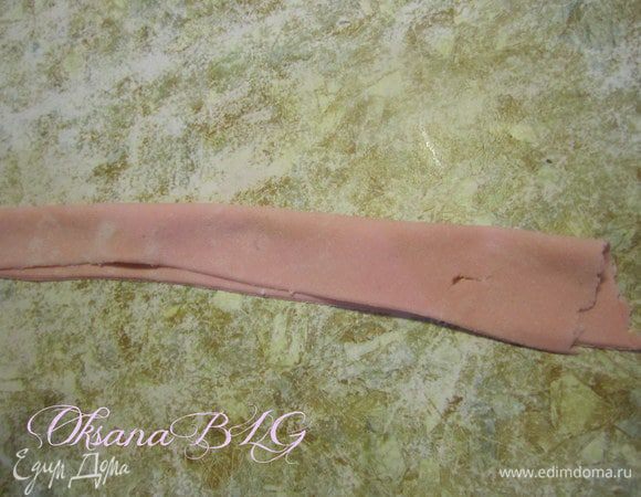 Раскатать мастику в длинную полоску, край смазать водой, сложить в двое.