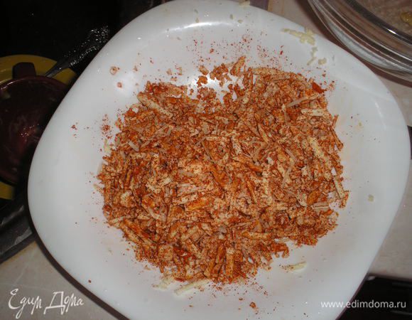 Тем временем натираем на терке с большими отверстиями сыр, добавляем к нему паприку, соль, перец.
