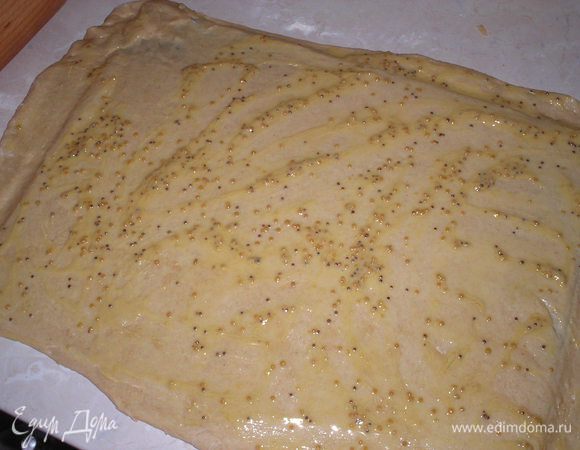 Тесто выкладываем на доску и раскатываем в прямоугольник размером 50*30 см. Смазываем смесью горчицы и масла.