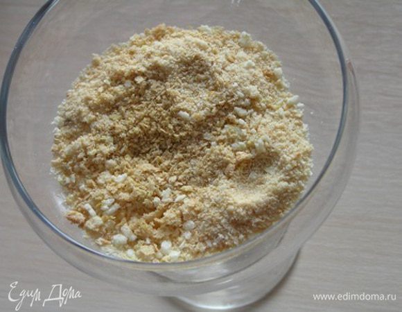 На дно креманок выложить измельченные кусочки бисквита или крошку. 