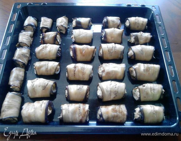 Свернуть баклажаны рулетиками и выложить их на противень (противень не надо смазывать маслом, т.к. баклажаны уже достаточно им пропитаны)