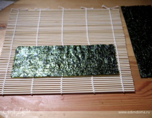 Приготовить циновку для скручивания роллов. Нарезать лист нори на 5 частей для лепестков. Приготовить первый лепесток.