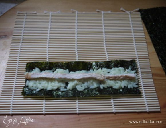 Положить в центр нори немного риса, сверху выложить полоску из куриной грудки. 