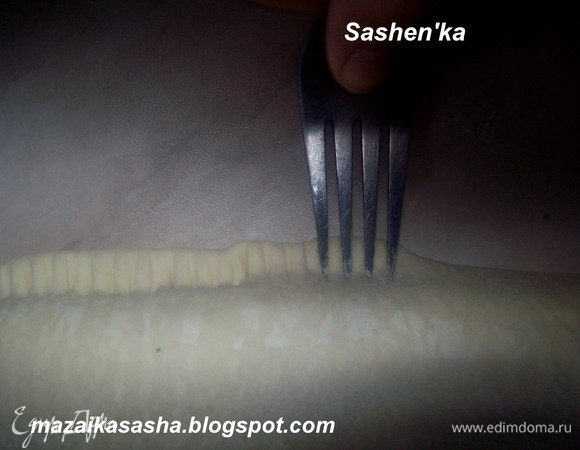 Взбиваем вилкой в миске яйцо и смазываем свободные места слоеного теста. Сворачиваем в рулет. Края скрепляем при помощи вилки.