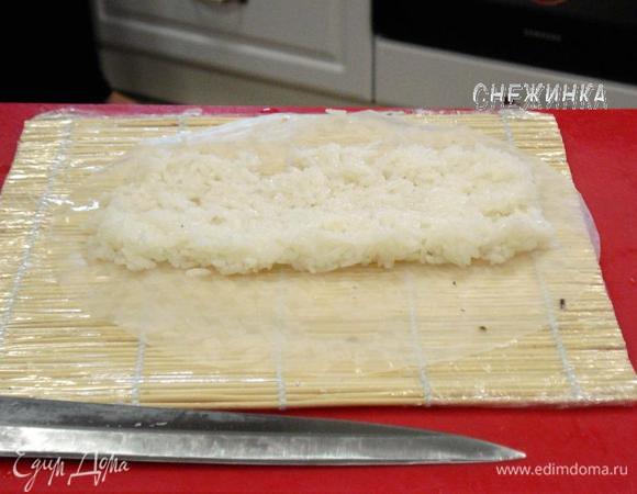 Рисовую бумагу с двух сторон смачиваем уксусной водой. Рис распределяем как и предыдущем варианте, но только по самому центру, оставив свободными края.