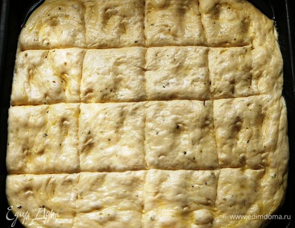 Достаем тесто из миски, обминаем его и придаем фокачче нужную форму. У меня традиционная лепешка. Выкладываем ее на противень, смазанный растительным маслом и оставляем на расстойку на 40 минут. Сделать на лепешке бороздки, смазать оливковым маслом.