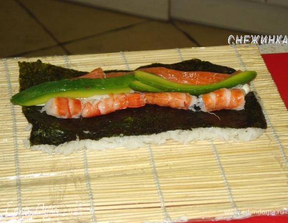 С дальней от сыра стороны выкладываем 2 креветки, с ближней – 2 полоски лосося, на сыр – пару ломтиков авокадо.

