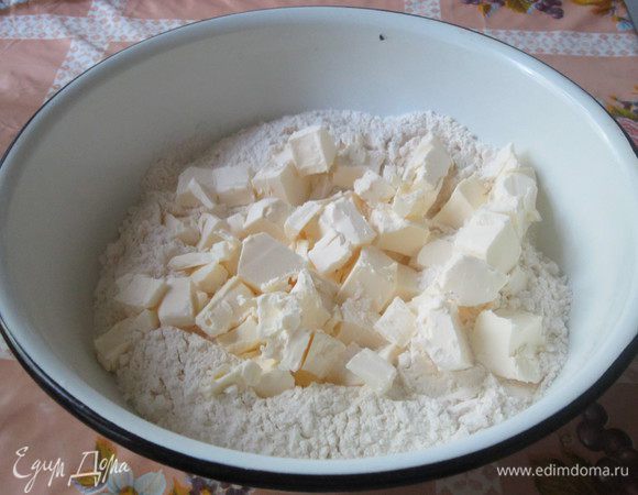 Просеиваем муку. На неё выкладываем нарезанное кусочками сливочное масло (или маргарин).