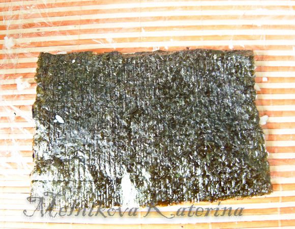 Положив ладонь на нори с рисом, перевернуть лист рисом вниз. 