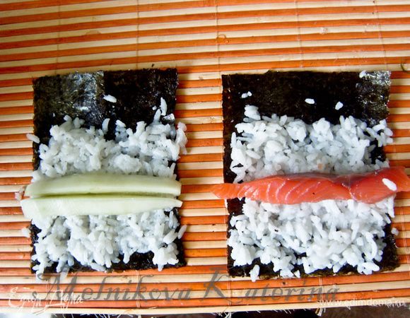 Выложить на обе части нори по небольшой горсти риса. Разровнять, оставляя с одного края "хвост" шириной примерно 2 см (ролл в дальнейшем будет держаться благодаря этому "хвосту"). На одну часть выложить огурец, но вторую часть - полоску лосося. 