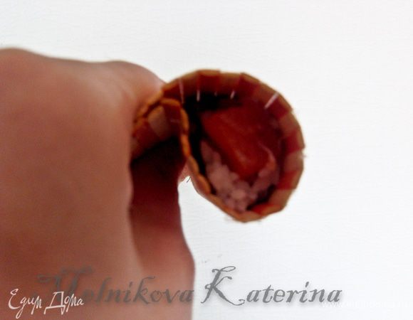 Взять одну из частей и при помощи коврика для суши сперва свернуть ее в рулет, а затем придерживая пальцами сформировать нечто похожее на запятую. Аналогичные действия проделать и со второй частью. 