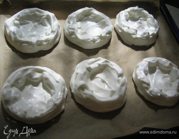 Застелить противень бумагой для выпечки, нарисовать на ней ровные кружки диаметром примерно по 10 см. Выложить белково-лимонную массу в виде тарталеток (с приподнятыми краями). У меня получилось 6 штук. Поставить в разогретый духовой шкаф на 30 минут (первые 10 минут - температура 150 гр, еще 20 минут - температура 100 гр)