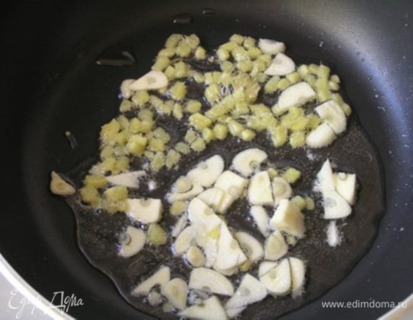 Пока варится рис, в большой сковороде хорошо разогреть оливковое масло. Высыпать мелко нарезанные чеснок и имбирь. Жарить 1 минуту. 