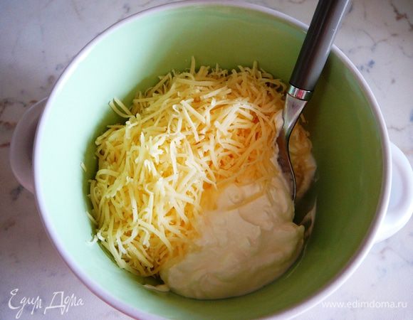 Сыр натереть на мелкой терке. Часть сыра соединить со сметаной и перемешать.