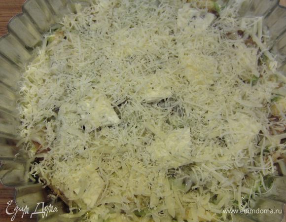 Положите кусочки чеддера. Сверху натрите на мелкой терке пармезан.