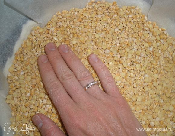 На тесто выложить лист пергамента и всыпать сухой горох или фасоль. Благодаря этому, тесто не будет подниматься. Отправить в духовку на 15 минут при температуре 200 градусов. 