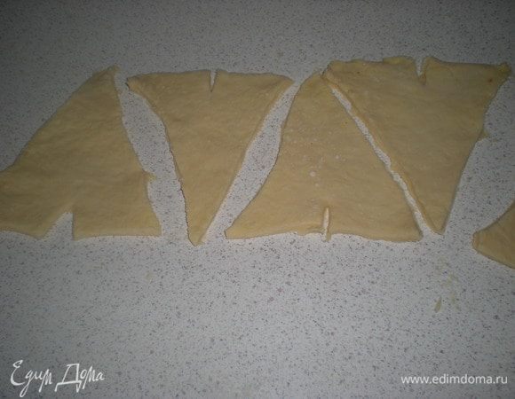 Обрезать не ровные края.Нарезать тесто на треугольники.В основании каждого треугольника нужно сделать маленький надрез,он поможет завернуть тесто в круассан.Как-то не досмотрела и видимо сильно увлеклась процессом,совсем забыла сфотографировать процесс заворачивания.Попробую описать.Берем с двух сторон за основание треугольника и начинаем заворачивать,немного растягивая в стороны от надреза.Не сжимайте сильно тесто-правильно свёрнутый круассан должен без особых усилий раскручиваться обратно.Выложить круассаны на противень(я простелила бумагой)смазать яйцом от центра к краю.Тогда излишки яичной смеси не будут склеивать тесто.