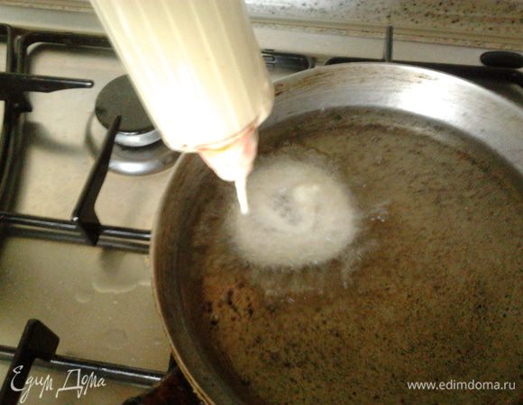 Теперь разогреваем масло в сковороде и с помощью кондитерского шприца выдавливаем спиралькой,как бы закручивая тесто опускаем во фритюр