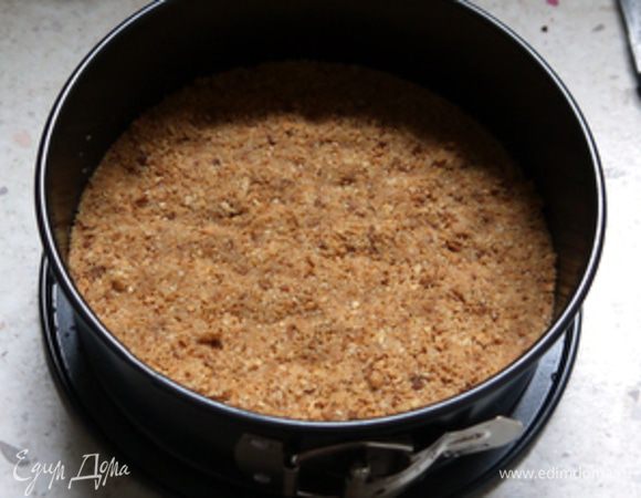 Форму для торта с разъёмным бортом  18 см в диаметре накрыть листом пергамента по размеру  и смазать маслом. Выложить смесь печенья с маслом и хорошо утрамбовать. Убрать в холодильник на 30 минут.

