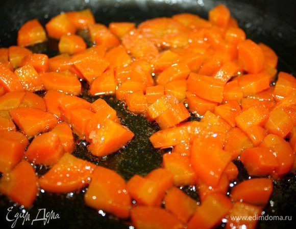 Морковь очистить и нарезать на небольшие кубики и потушить на оливковом масле до готовности.Готовую морковь переложить на бумажное полотенце,чтобы удалить излишки масла.В сковороду высыпать сахар и  раздавленный ножом чеснок и прогреть сковороду до растворения сахара.Добавить морковь и удалить чеснок.Сначала карамель очень пахнет чесноком,но,после добавления моркови запах чеснока заметно уходит.Смешать морковь с карамелью(у меня карамель получилась светлой),чеснок удалить(он уже стал безвкусным).Мне кажется,что морковь стала ещё более морковной:)) и в меру сладкой. 