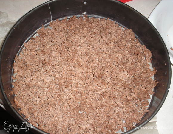 Форму для выпечки застилаем пергаментом.  В форму на терке с большыми отверстиями натираем половину теста, равномерно распределяем.