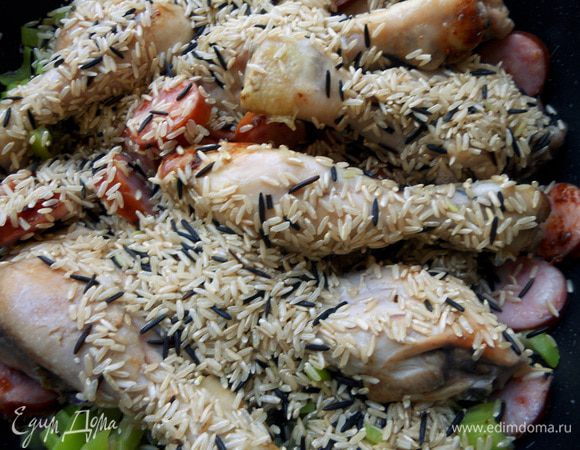 В сковороду вернуть курицу и колбаски, засыпать рис. 