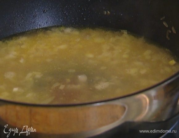 Всыпать рис, дать ему пропитаться ароматами лука и масла. Когда рис станет прозрачным, залить его горячим бульоном так, чтобы он покрыл рис на полпальца. Закрыть крышкой и готовить 15 минут.
