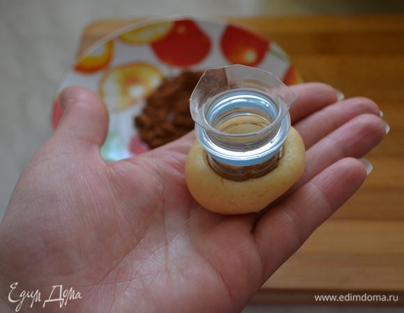 Затем от простой пластиковой баклажки отрезаем горлышко. Затем от теста отрываем маленький кусочек, катаем в шарик, горлышко от бутылки погружаем в какао и слегка продавливаем шарик теста.