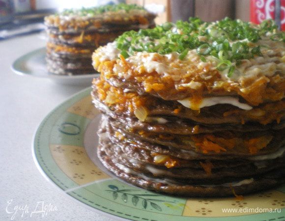 Собрать торт, промазывая каждый блинчик морковью с луком, затем чесночной заправкой. Украсить зеленью.