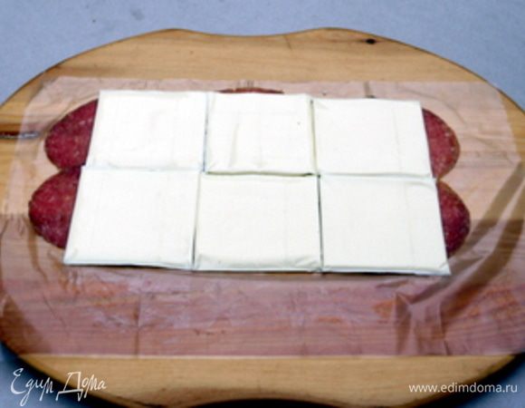 На рабочей поверхности ,накрытой пергаментом, разложить тонко нарезанные ломтики салями. Сверху на салями распределить пластинки сыра.