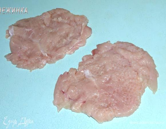 Куриную грудку отделить от кости, чтобы получилось 2 филе. Отбить их между двумя пластами пищевой пленки, по возможности формируя округлую форму.