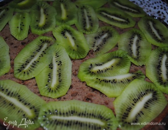 Смешать чай и ликер, пропитать нижний корж, и выложить порезанное киви. 