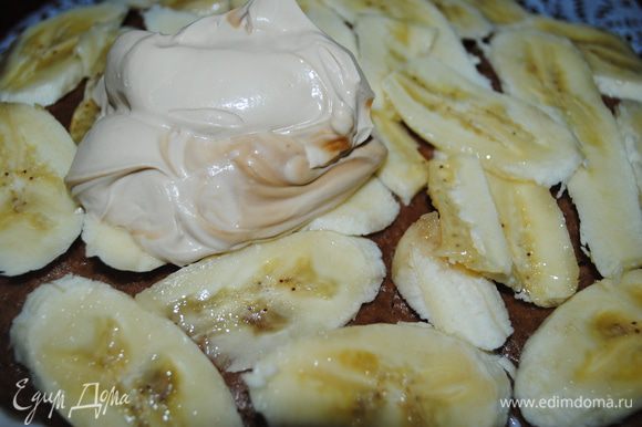 Когда йогурт застынет, на него положить еще один корж, немного пропитать чаем, выложить порезаные бананы и смазать кремом.