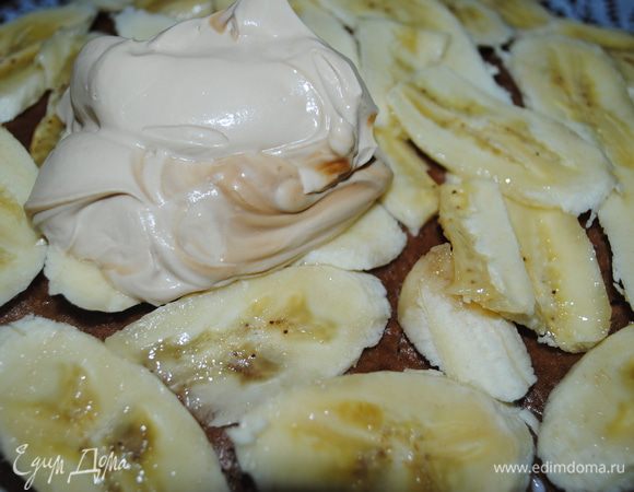 Когда йогурт застынет, на него положить еще один корж, немного пропитать чаем, выложить порезаные бананы и смазать кремом.
