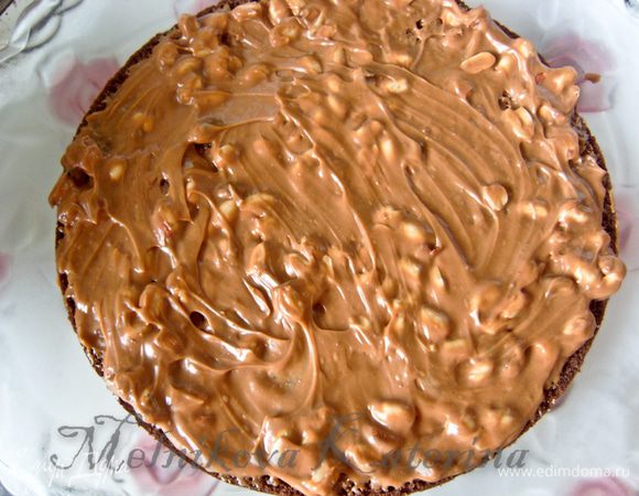 Теперь сборка. Выкладываем первый корж и смазываем половиной крема с орехами. 