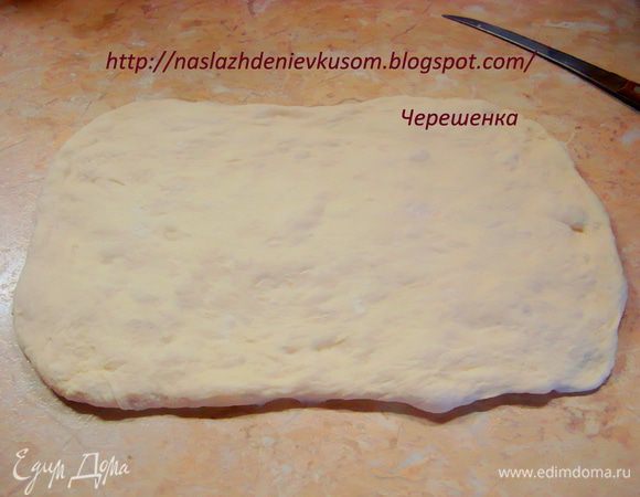 Одну убираем в пакетик и отставляем в сторону. Вторую аккуратно, на столе, посыпанном небольшим количеством пшеничной муки, разглаживаем руками в прямоугольник, размером примерно 15 на 30 см, толщиной 1см…