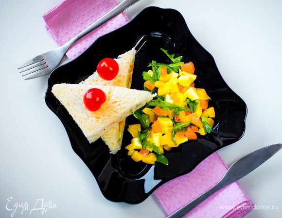 Срезаем с сэндвича корочку, режем сэндвич на треуголники, протыкаем зубочисткой и украшаем половинками помидорок черри