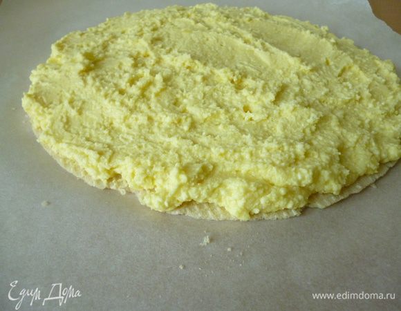 Теперь берем лист пергамента и кладем на него вафельный корж. Коржи бывают разные: с плотной структурой и более рыхлые. Если у вас коржи потверже (в моем случае именно такие, как для фасовки мороженого), то тогда с помощью кисточки слегка смажьте корж сметанной смесью. Затем ложкой наносим на корж творожную массу слоем 2-2,5 см  и подождем пока смесь смягчит вафельный корж.