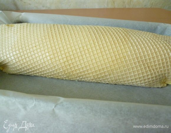 Аккуратно свертываем рулет и поворачиваем его швом вниз. Вместе с пергаментом переносим рулет в форму для запекания.