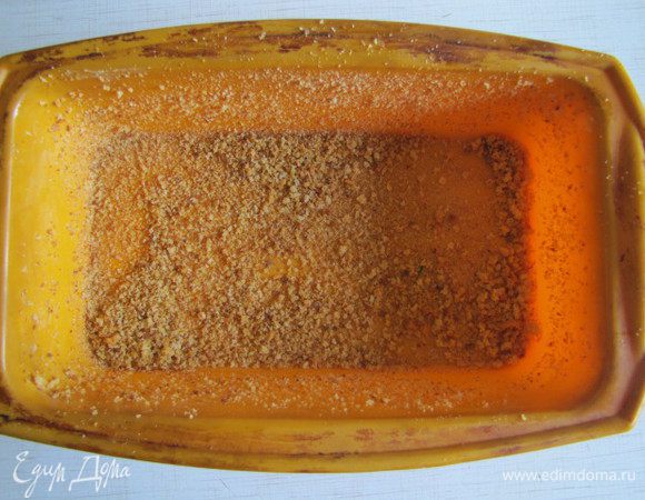 Форму для террина смазать маслом и обсыпать панировочными сухарями. Половину куриного фарша выложить в форму.