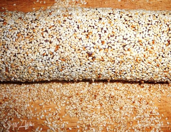 Тесто достать из холодильника. Скатать колбаской и хорошо обвалять в кунжуте.