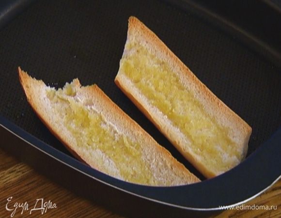 Выложить хлеб на противень срезами вверх, сбрызнуть оливковым маслом и обжаривать в разогретой духовке до появления золотистой корочки.