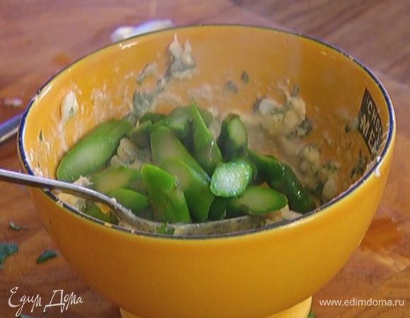 Слить воду из спаржи, верхушки отложить, а кусочки стеблей перемешать с заправкой.