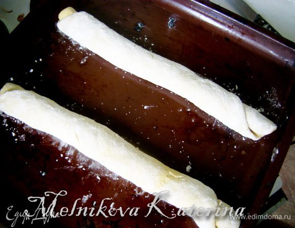 Должно получиться два рулета. Смазать противень сливочным маслом и выложить рулеты. Накрыть тканью и оставить на 30 минут для подхода в теплом и укромном месте. 