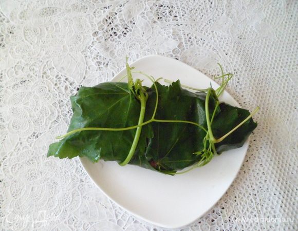 На разделочную доску выложить виноградные листья и завернуть в них готовое филе. Если у Вас нет кулинарной нити, то в качестве нити можно использовать свежую и нежную лозу. 